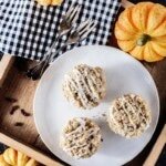 Saftige Kürbis-Muffins mit Zierkürbissen auf einem Holztablett